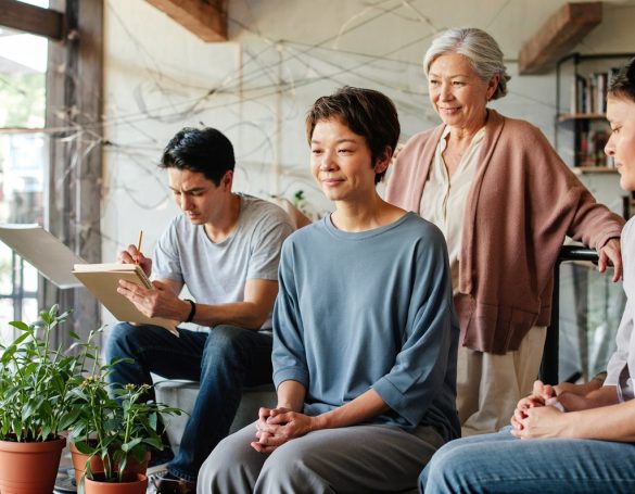 A group of four people engaging in conversation in a cozy, well-lit living space.